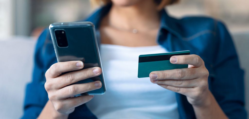 young woman holding white credit card for shopping online